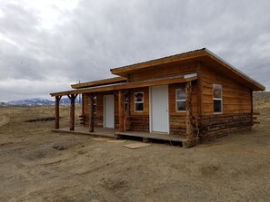 A wooden cabin with a porch, a door, and windows. - Monster Lake Ranch (Cody)
