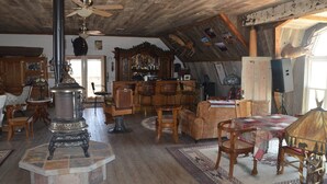 A rustic interior with a large fireplace, wooden furniture, and a bar area. - Monster Lake Ranch (Cody)