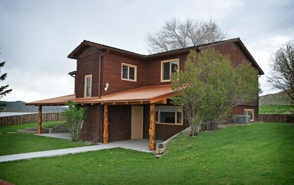 A two-story wooden house with a covered porch, a garage, and a small shed. - Monster Lake Ranch (Cody)