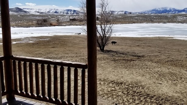 A wooden deck with a view of a snowy landscape and mountains. - Monster Lake Ranch (Cody)