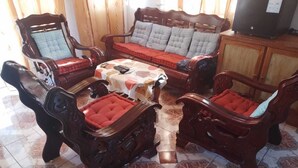 Uma sala de estar com sofá, duas poltronas, uma mesa de centro e uma televisão.