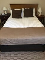 Una habitación de hotel con una cama grande, dos mesitas de noche, un teléfono y dos lámparas.