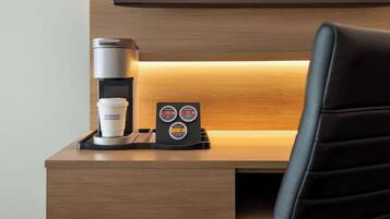 Eine Kaffeemaschine mit Tasse und einer Halterung für eine Bonuskarte auf einem Holztisch.
