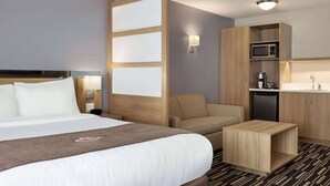 Ein Hotelzimmer mit einem großen Bett, einem Sofa, einem kleinen Tisch, einer Mikrowelle und einem Waschbecken.