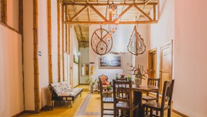 Un comedor acogedor con una mesa y sillas de madera, un banco y adornos colgantes.