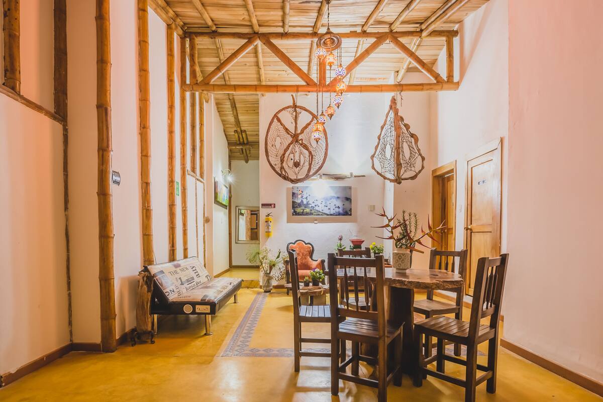 A cozy dining area with a wooden table and chairs, a bench, and hanging decorative items.