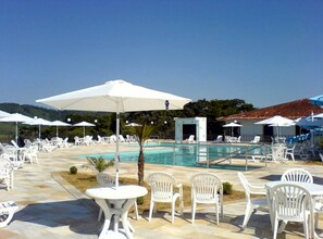A poolside area with white chairs and umbrellas, a small pool, and a clear sky. - JS Park Hotel (Sao Lourenco)