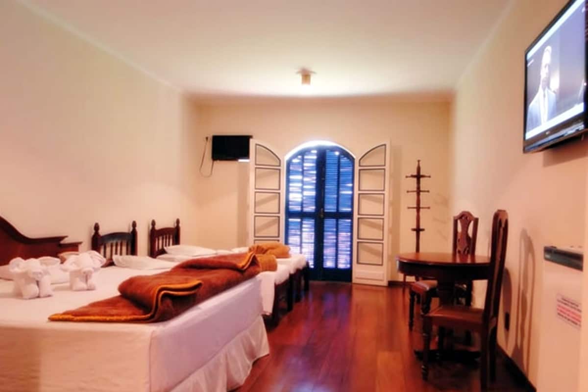 A hotel room with two beds, a dining table, and a television.