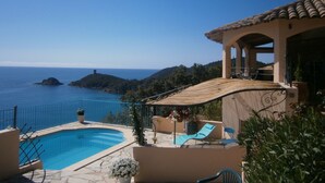 A pool area with a view of the sea, a covered seating area, and a building with a tiled roof. - Villa with pool and private Spa facing the sea (Conca)