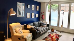 Una sala de estar moderna con una pared azul de acento, un sofá de cuero, un sillón blanco y una mesa de centro.