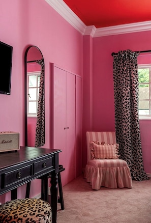 Une pièce rose avec un bureau, une chaise et une armoire.