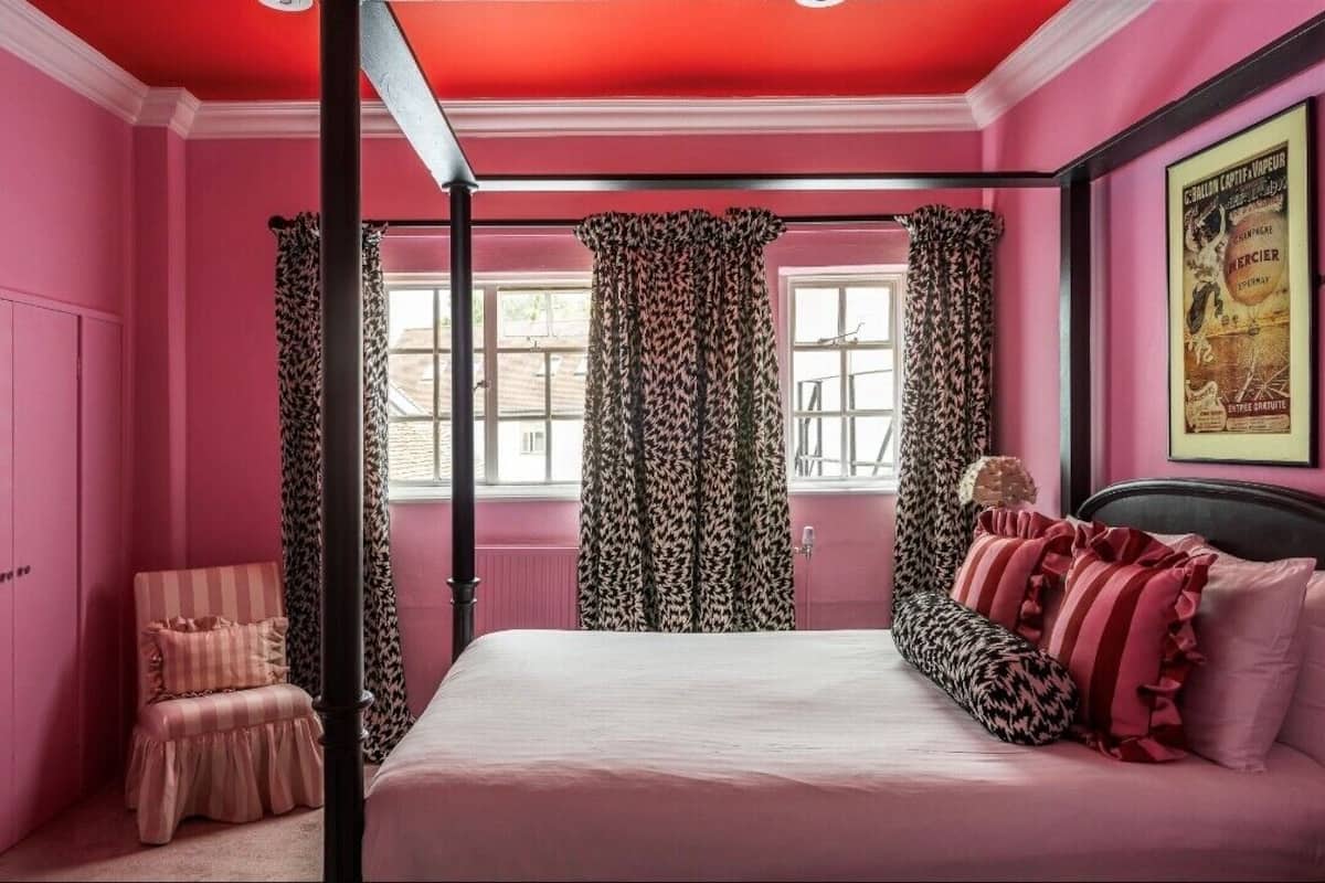 Un dormitorio con una cama, una silla, un ventanal y cortinas.