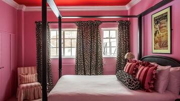 Un dormitorio con una cama, una silla, un ventanal y cortinas.