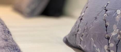 Una cama con colchón blanco y manta azul.