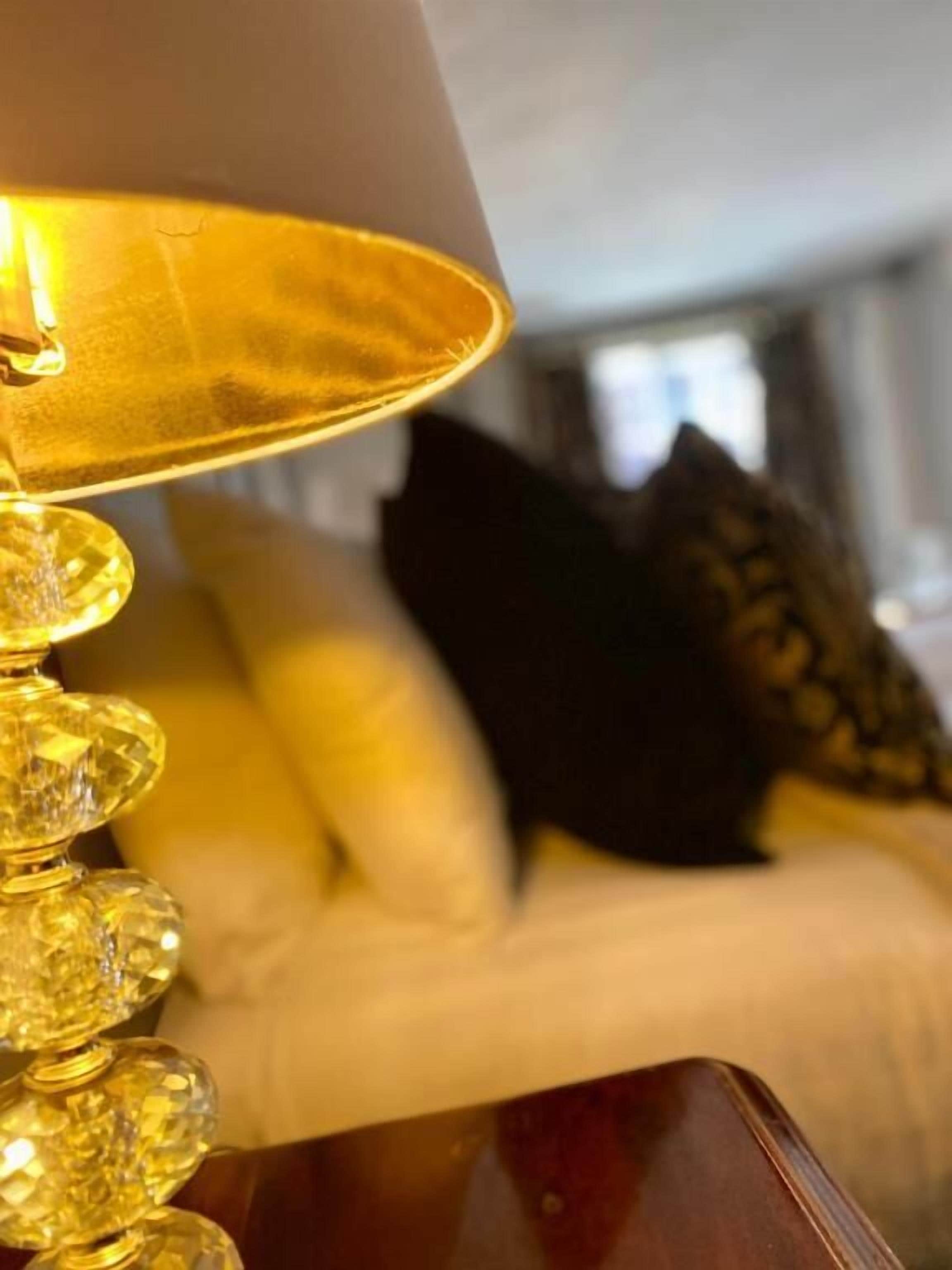 A close-up of a lamp with a golden shade and a wooden base.