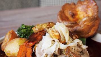 Une assiette de nourriture comprenant du poulet rôti, des carottes, des pommes de terre et un Yorkshire pudding.