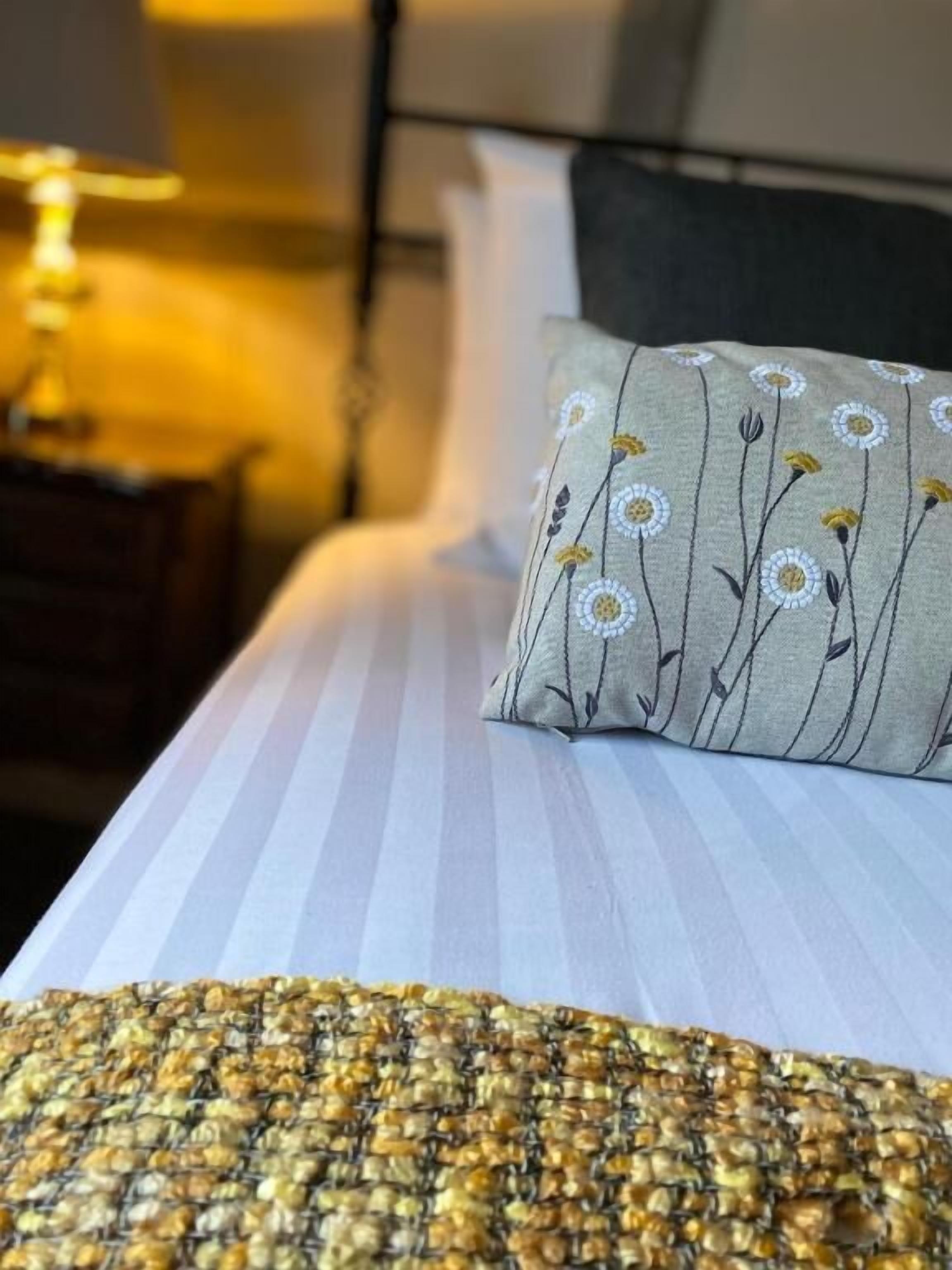 A bed with a striped bedspread and a pillow with a floral pattern.
