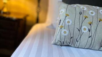 A bed with a striped bedspread and a pillow with a floral pattern.