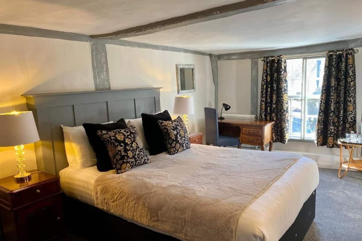 Habitación de hotel con una cama grande, un escritorio, una silla y una ventana con cortinas.