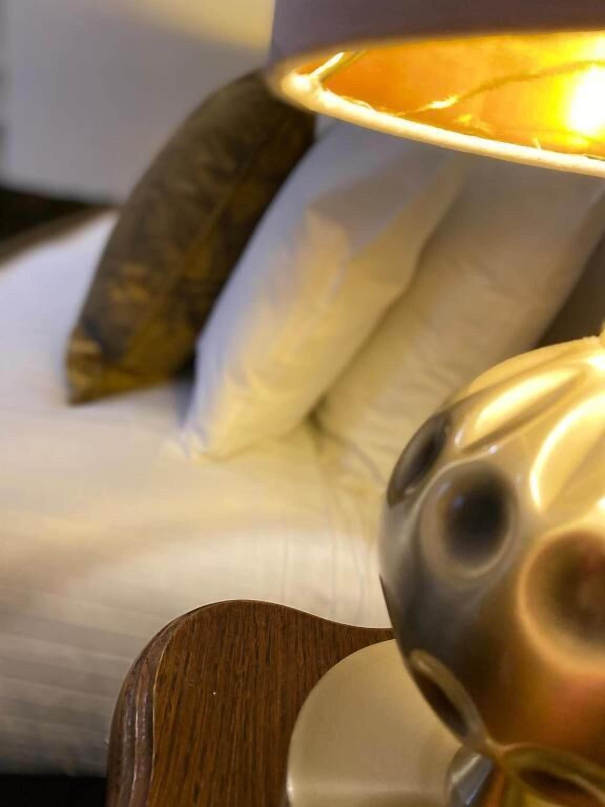 Een foto van een lamp met een witte kap en een houten voet.