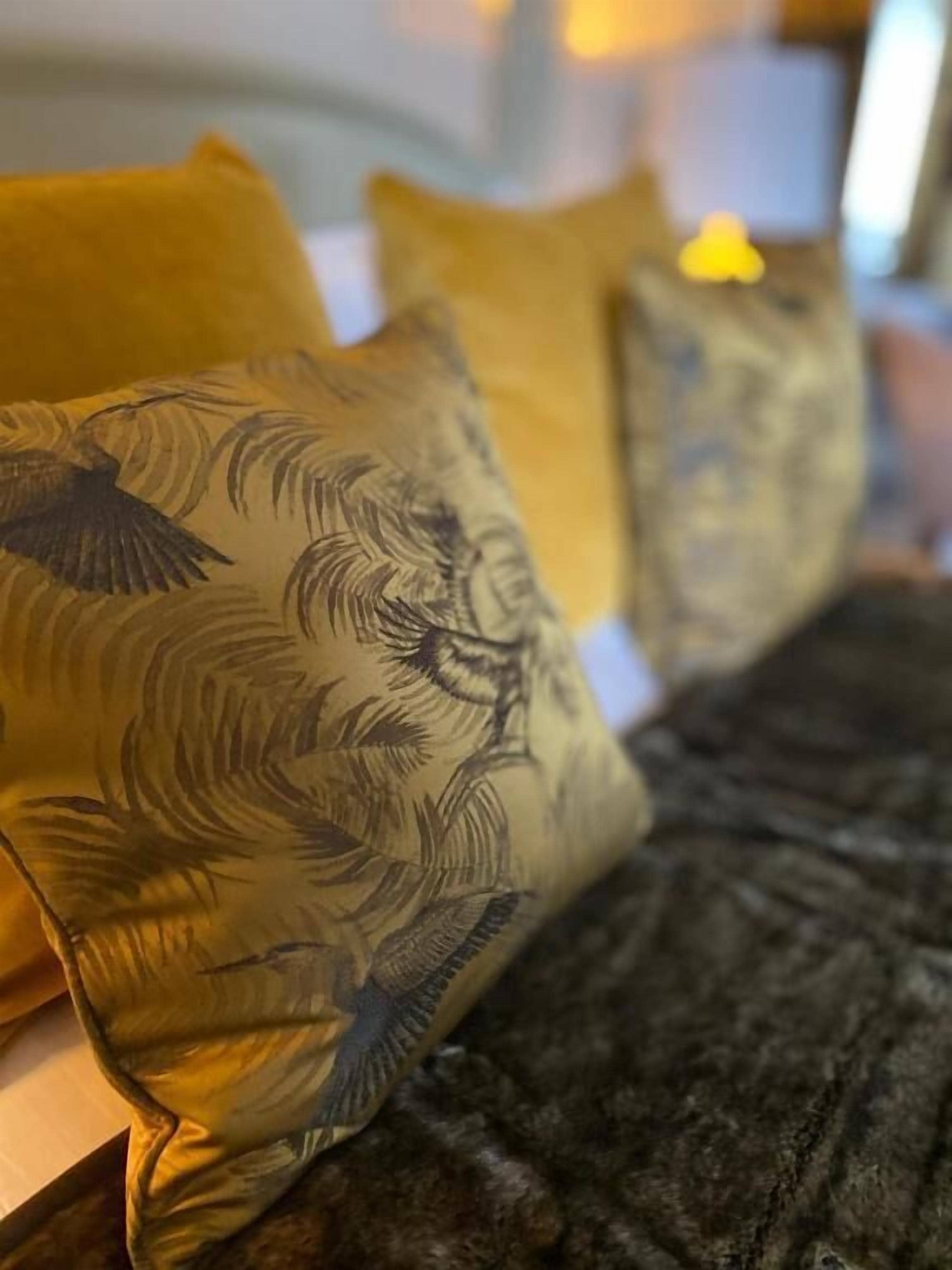 A bed with a dark, textured bedspread and pillows with a bird and leaf pattern.