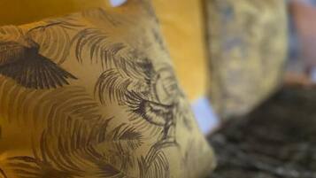 A bed with a dark, textured bedspread and pillows with a bird and leaf pattern.