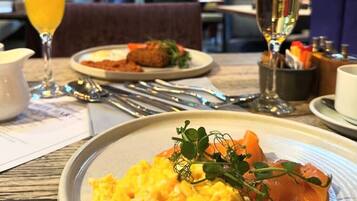 A breakfast setting with scrambled eggs, smoked salmon, and a glass of orange juice.