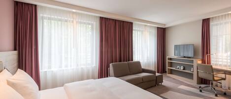 Une chambre d’hôtel avec un grand lit, un canapé, un bureau et une télévision.
