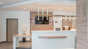 A modern reception desk with a wooden finish, a digital screen, and a sign indicating it's a Hilton hotel. - Hampton by Hilton Frankfurt City Centre East (Frankfurt)