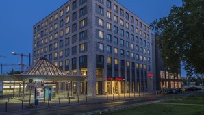 A multi-story hotel with a modern design, featuring a prominent entrance with a glass canopy and a visible restaurant named "Hampton." - Hampton by Hilton Frankfurt City Centre East (Frankfurt)