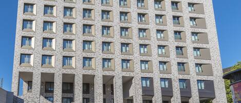 A multi-story building with a uniform facade, rectangular windows, and a central entrance.