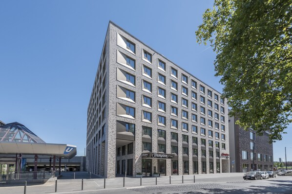 A modern hotel with a symmetrical facade, multiple balconies, and a prominent entrance.