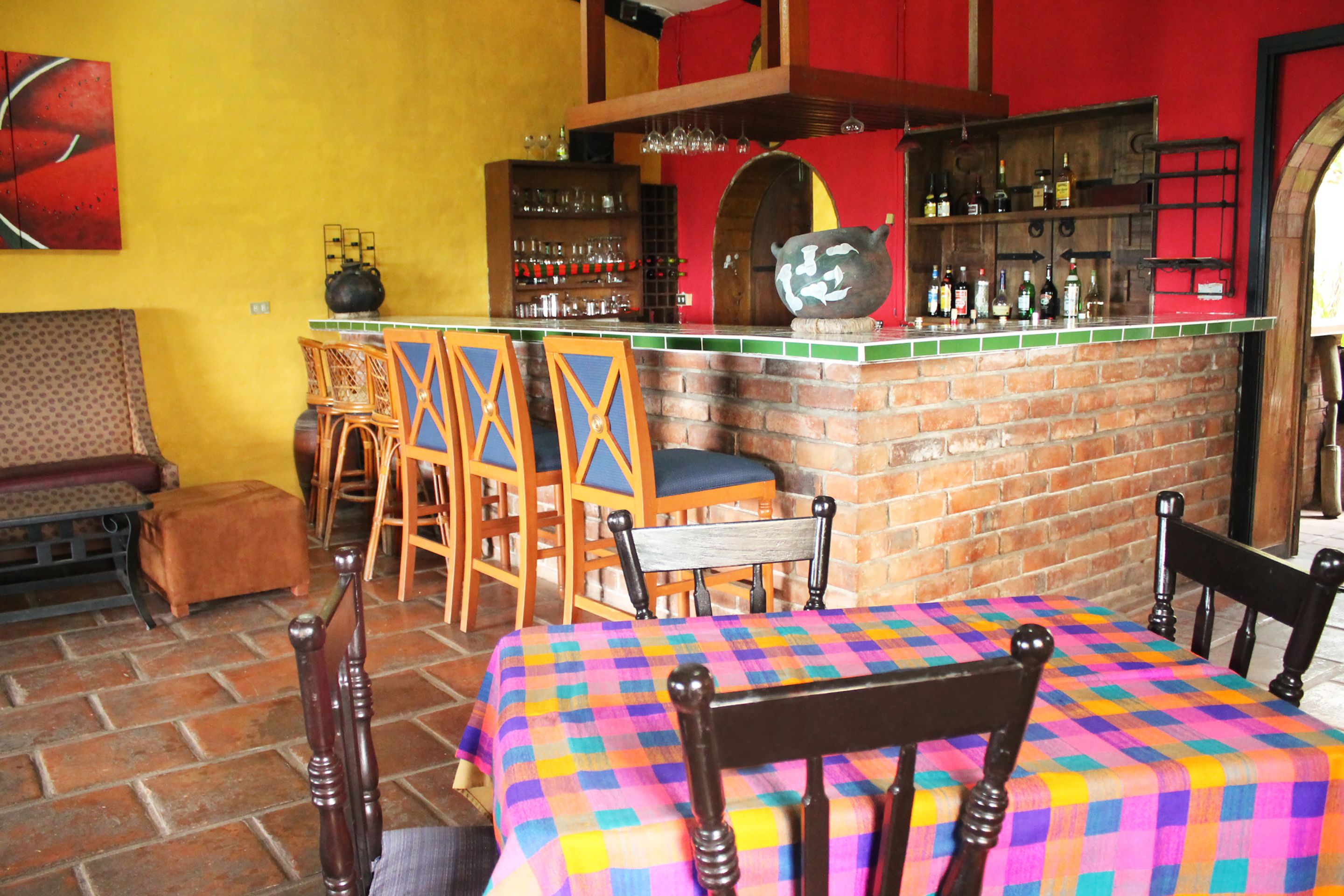 A bar area with a brick counter, multiple chairs, and a colorful tablecloth.