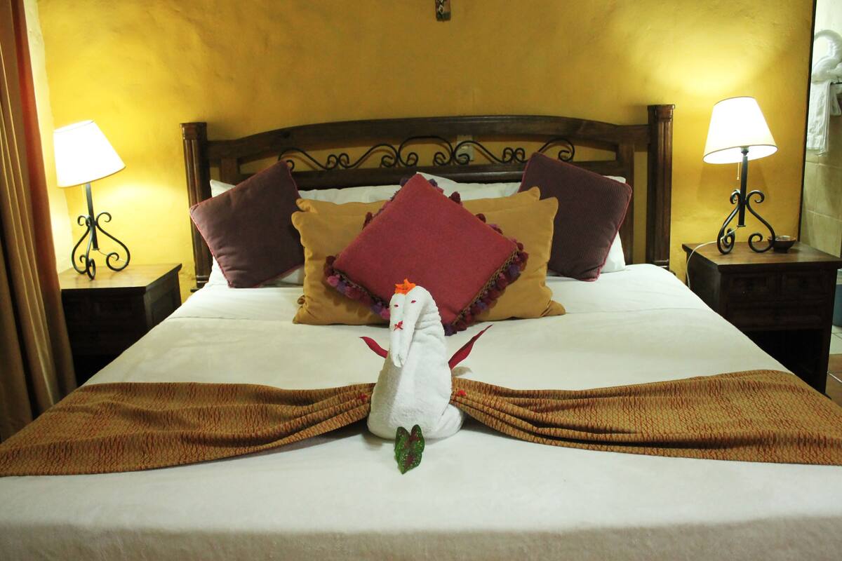 A neatly made bed with a decorative pillow arrangement, two bedside lamps, and a unique white decorative item on the bed.