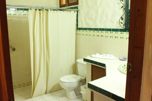 Un baño con inodoro, cortina de ducha y lavamanos con espejo.