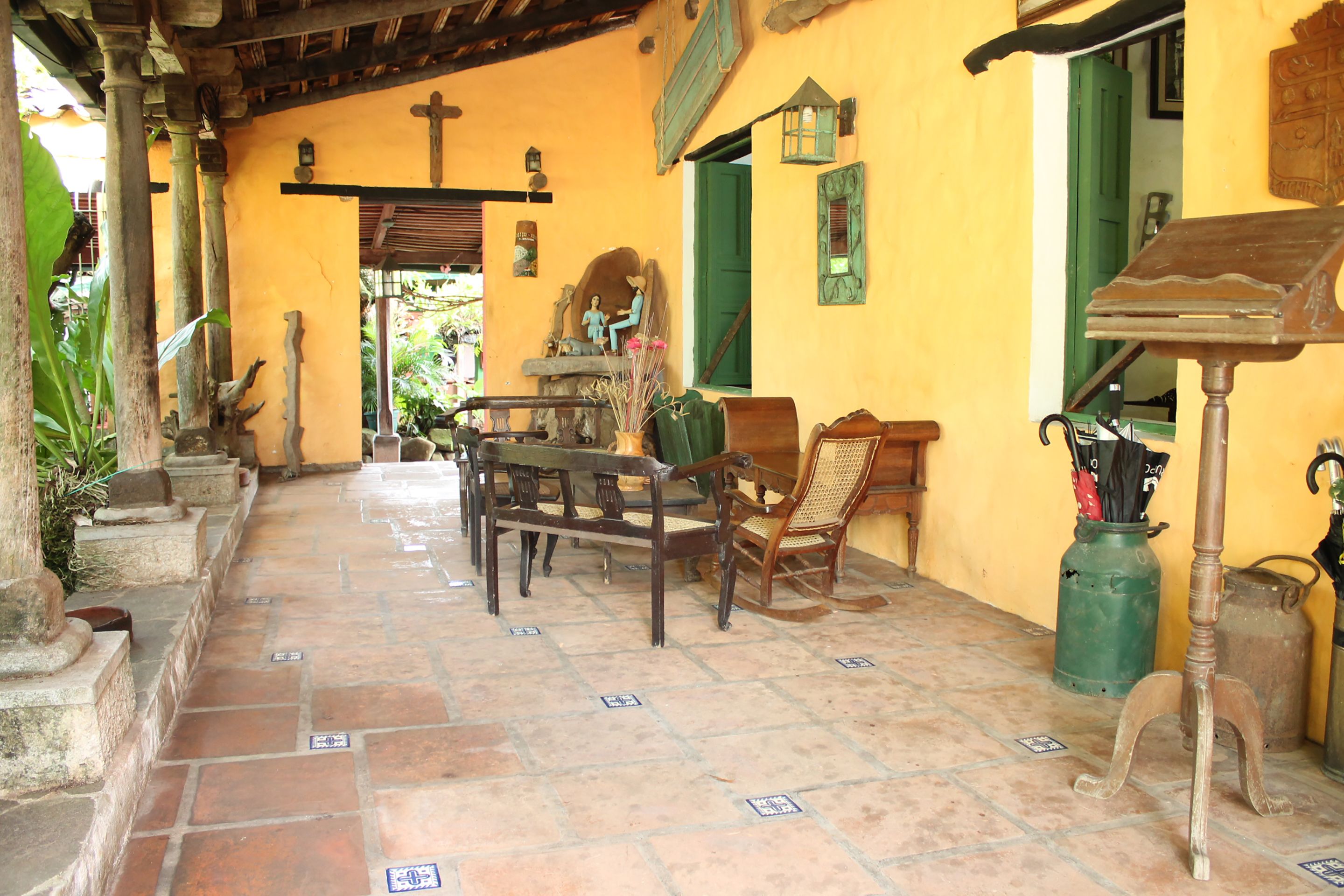 A courtyard with a wooden table and chairs, a green door, and a small statue.