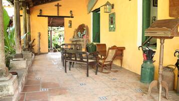 A courtyard with a wooden table and chairs, a green door, and a small statue.