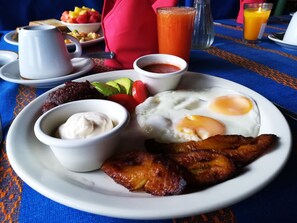 Un plato de desayuno con huevos, tocino, aguacate y fruta.