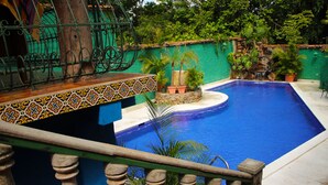 A pool with a tiled edge, surrounded by greenery and a stone wall.