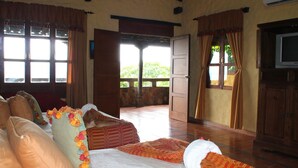 A room with a bed, a television, and a view of the outdoors.