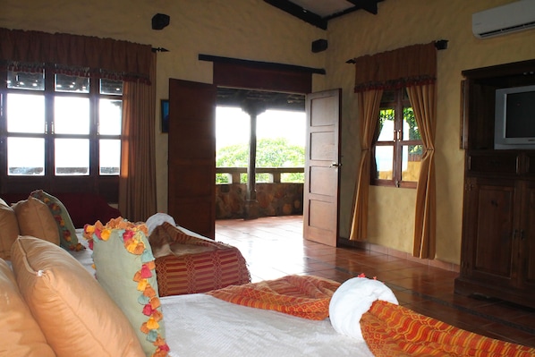 A room with a bed, a television, and a view of the outdoors. - La Posada de Suchitlán (Suchitoto)