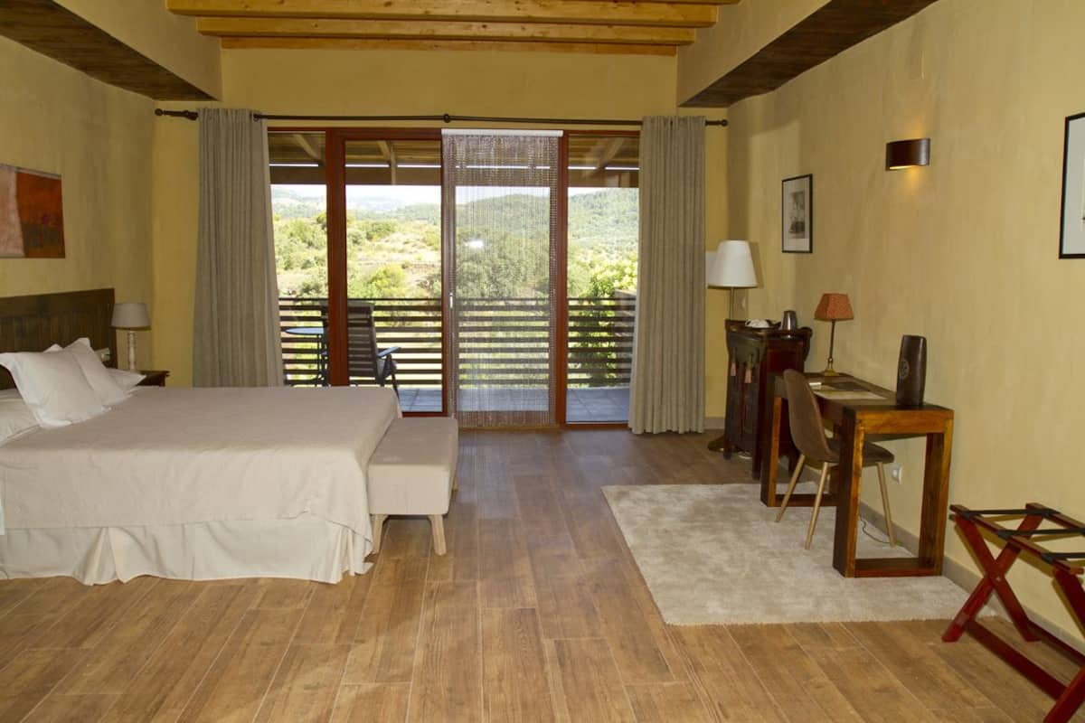 A bedroom with a bed, a desk, and a view of the outdoors.