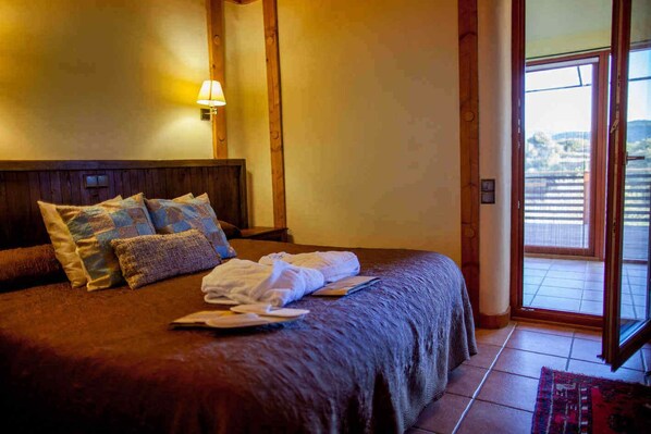 A hotel room with a large bed, a wooden headboard, a nightstand with a lamp, and a view of the outside through a sliding door.