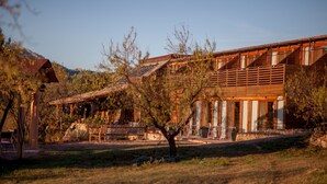 A modern building with a wooden exterior, large windows, and a patio area with outdoor seating. - Mas del Bot (Valderrobres)