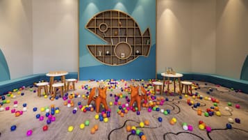 Playful space for kids with a circular bookshelf, two dining tables, and colorful balls.