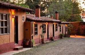 A row of rustic buildings with brick walls and tiled roofs, each with a small porch and potted plants. - Villa Patzcuaro Garden Hotel & RV Park (Patzcuaro)