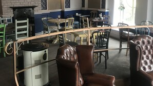Interior de restaurante con pared de ladrillo, arcos, chimenea y comedor con mesas y sillas.