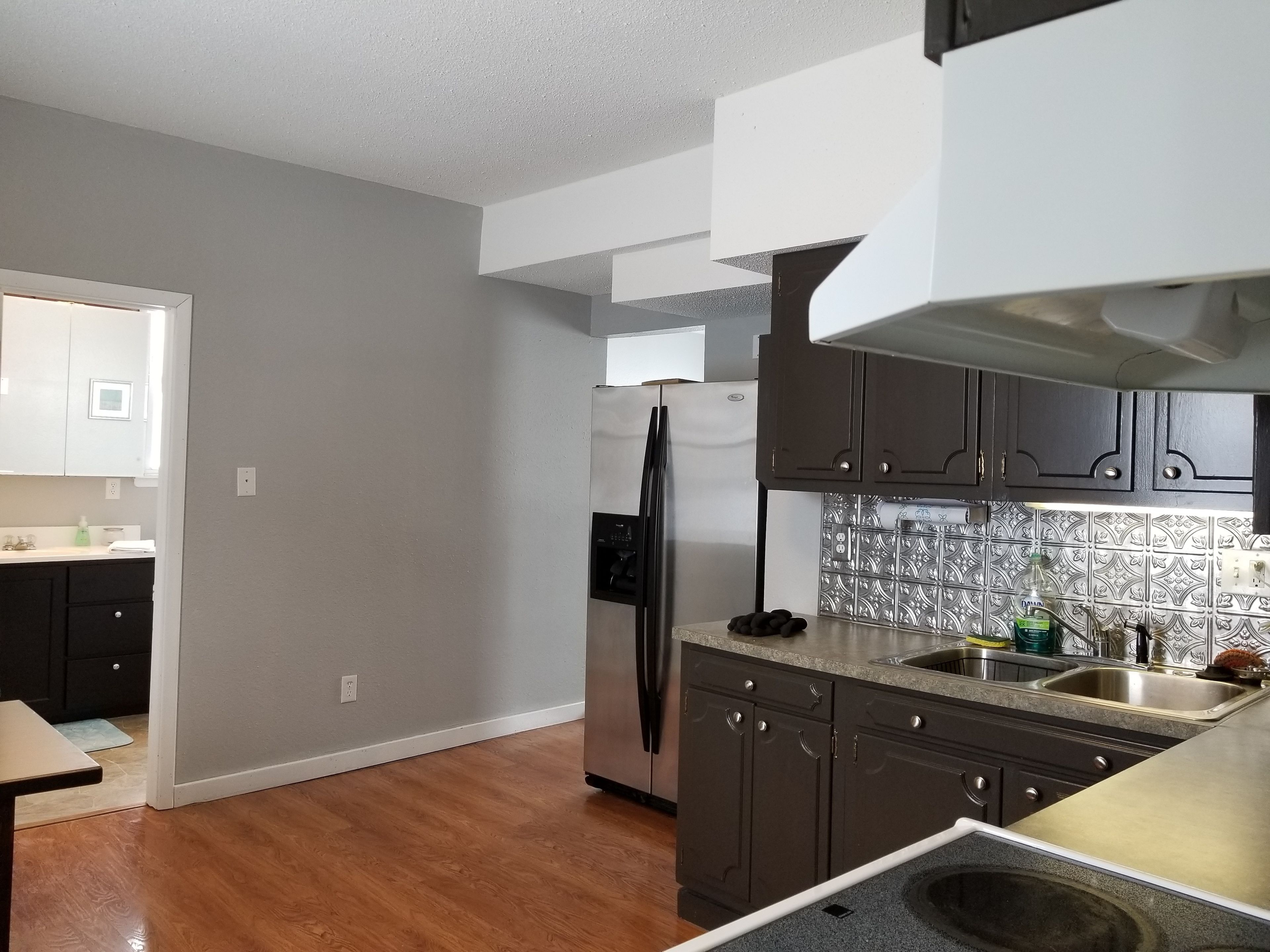 A modern kitchen with dark cabinets, a stainless steel refrigerator, and a patterned backsplash.