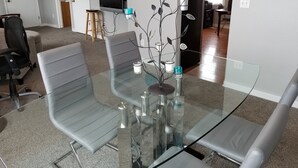 Ein moderner Konferenzraum mit einem Glastisch, grauen Stühlen, einer kleinen Pflanze und einem Fernseher an der Wand.