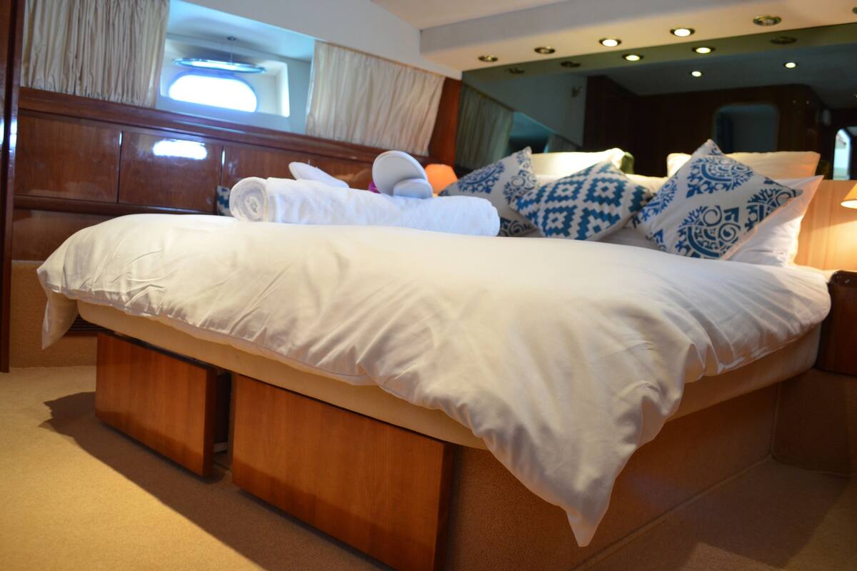 A large bed with white linens, blue patterned pillows, and a wooden headboard.